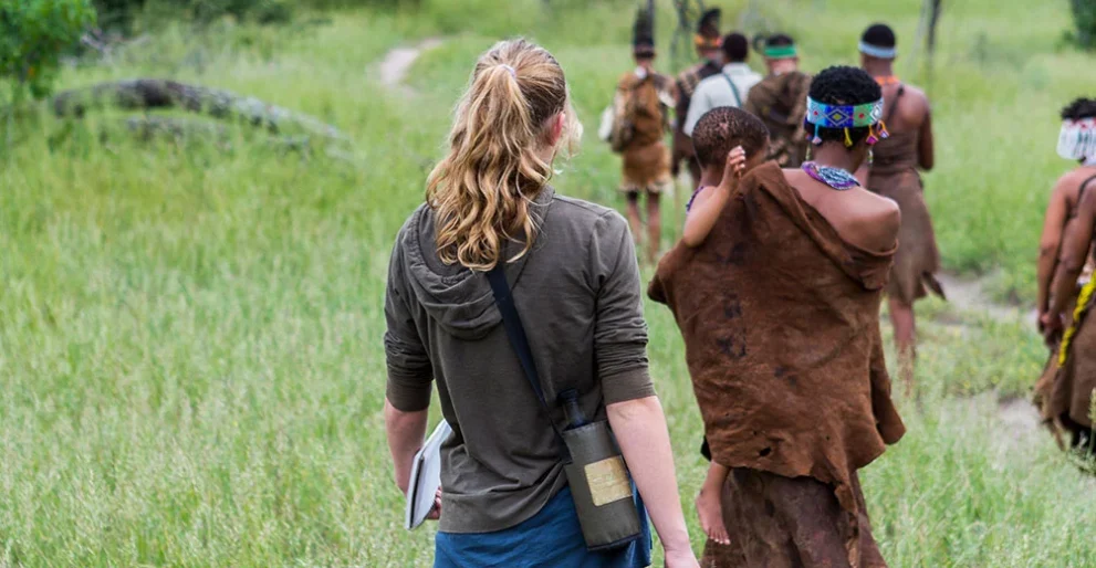 Eine Frau läuft mit afrikanischen Einheimischen durch die Savanne