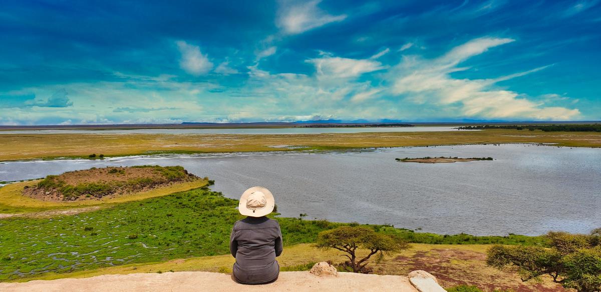 Safari-Touristin schaut auf dem Observation Hill im Amboseli über die weite Ebenen de Nationalparks