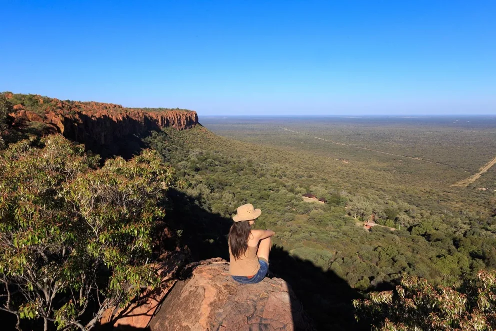 Frau sitzt an einem Aussichtspunkt des Waterberg Plateaus.