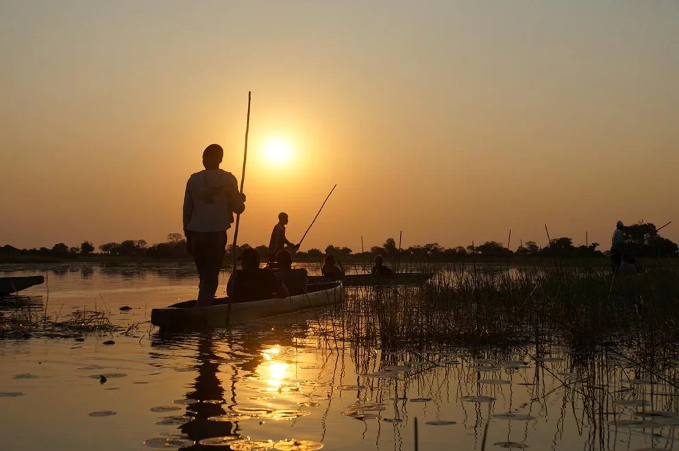 Traditionelle Boote im Spnnenuntergang im Okavango Delta.