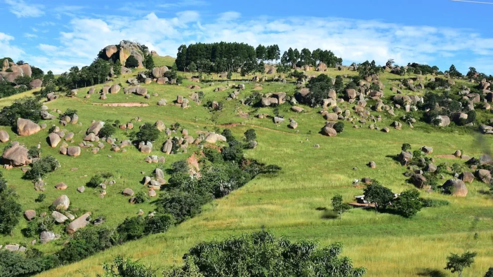 Steine verteilt auf einem grünen Hügel im Swasiland.