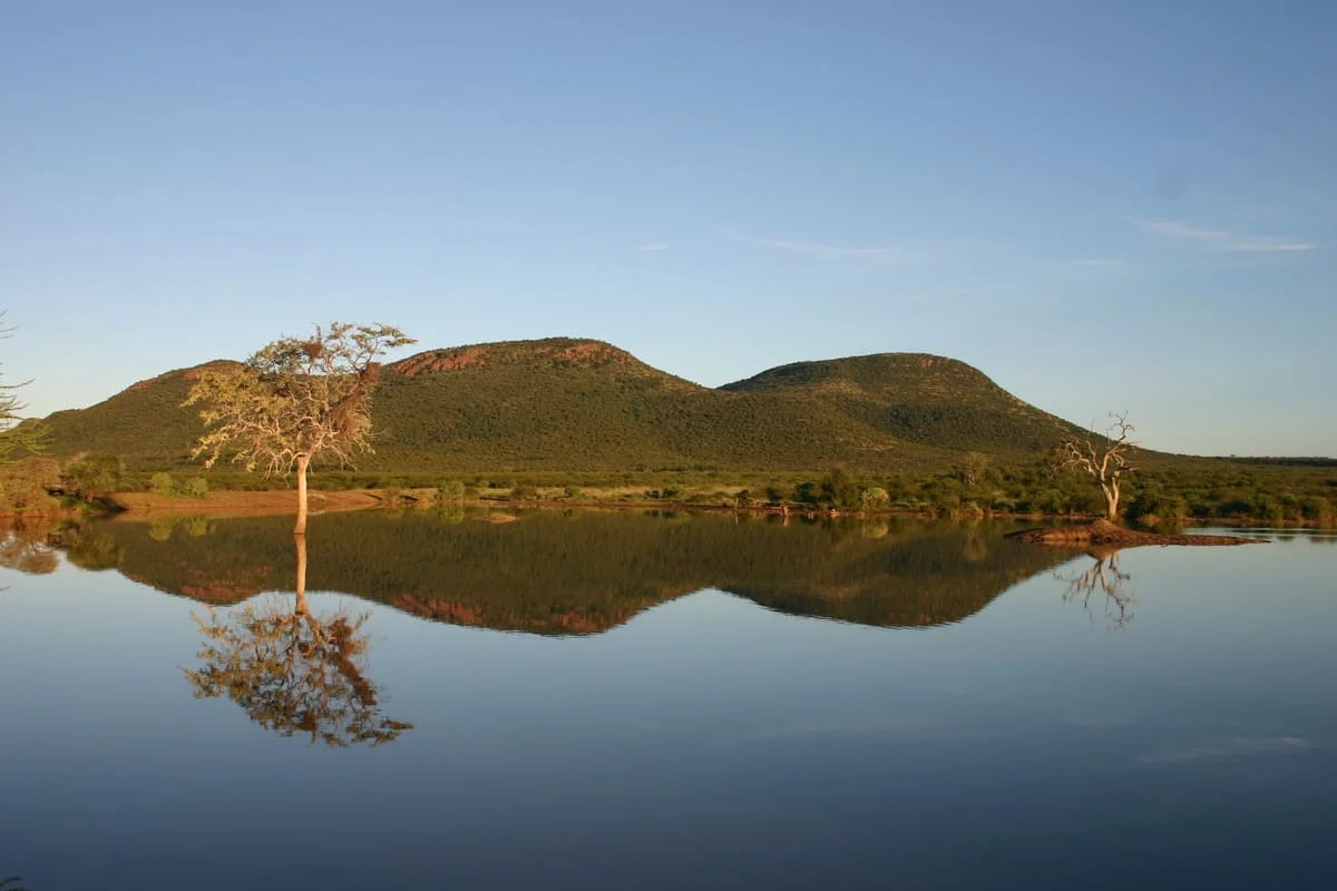 Berge spiegeln sich im Fluss im Madikwe Game Reserve.