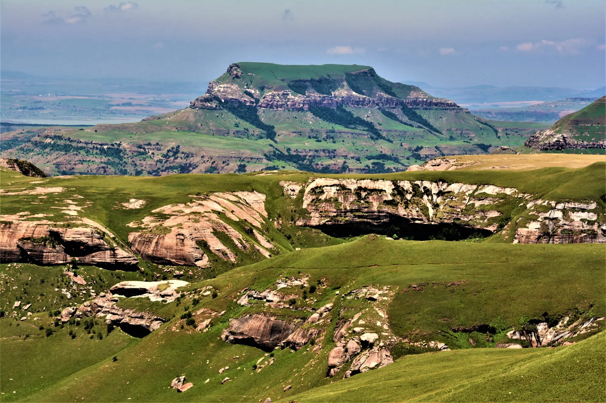 Grüne, hügelige Landschaft mit markanten Felsformationen unter klarem Himmel. Ideal für Naturfreunde.