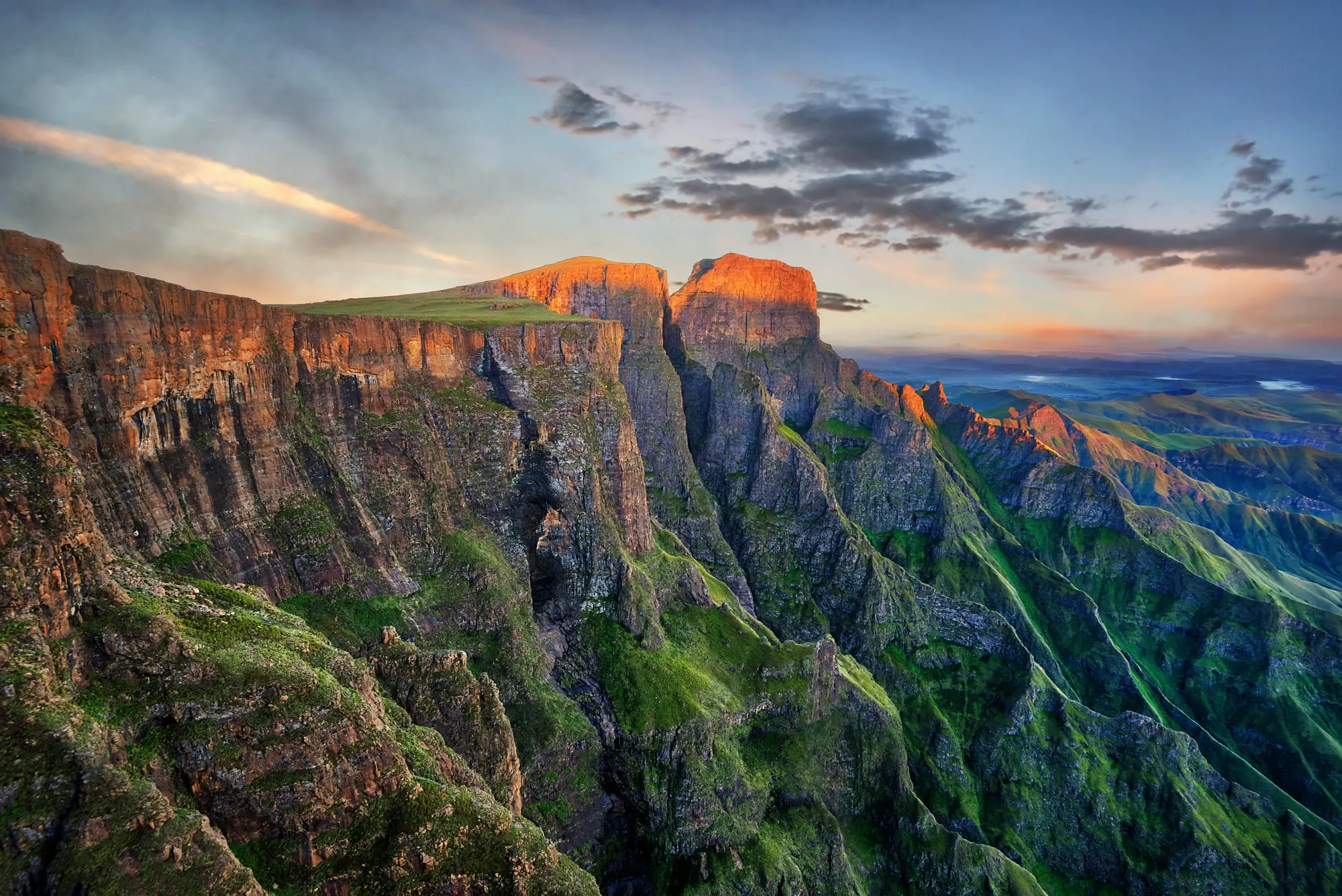 Atemberaubende Berglandschaft bei Sonnenuntergang mit steilen Klippen und grünen Tälern. Ideal für Naturfotografie.